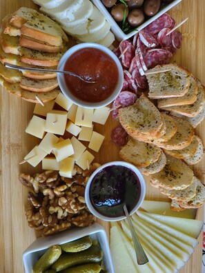 A charcuterie board with various cheeses, nuts, pickles, and bread. - Quinta de Cypriano - Wine & Nature (Ponte da Barca)