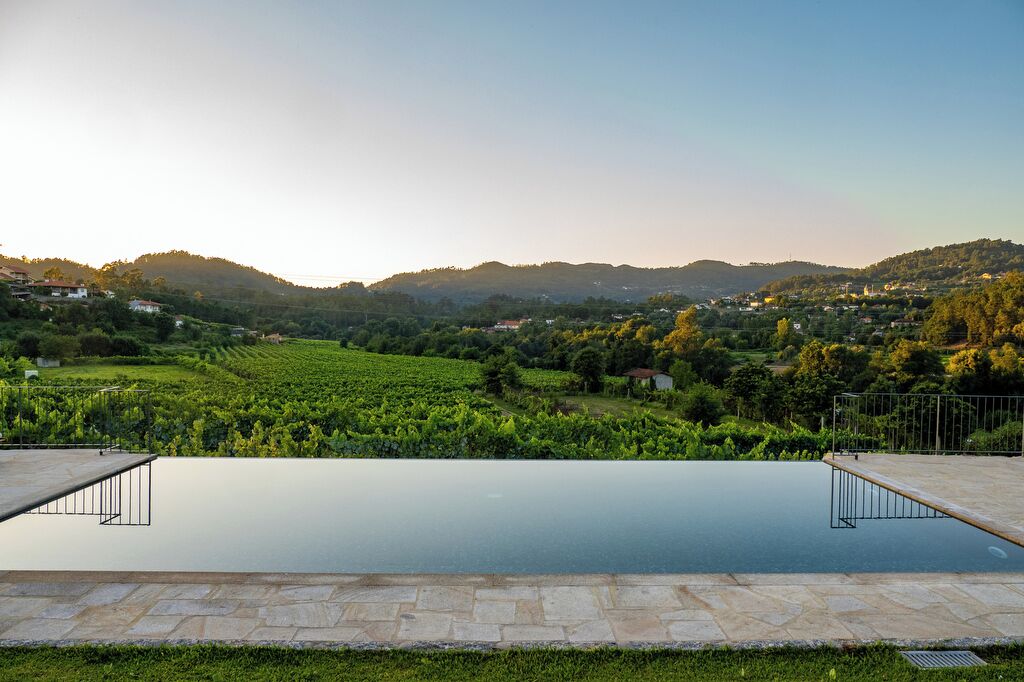 A swimming pool with a view of vineyards and hills.