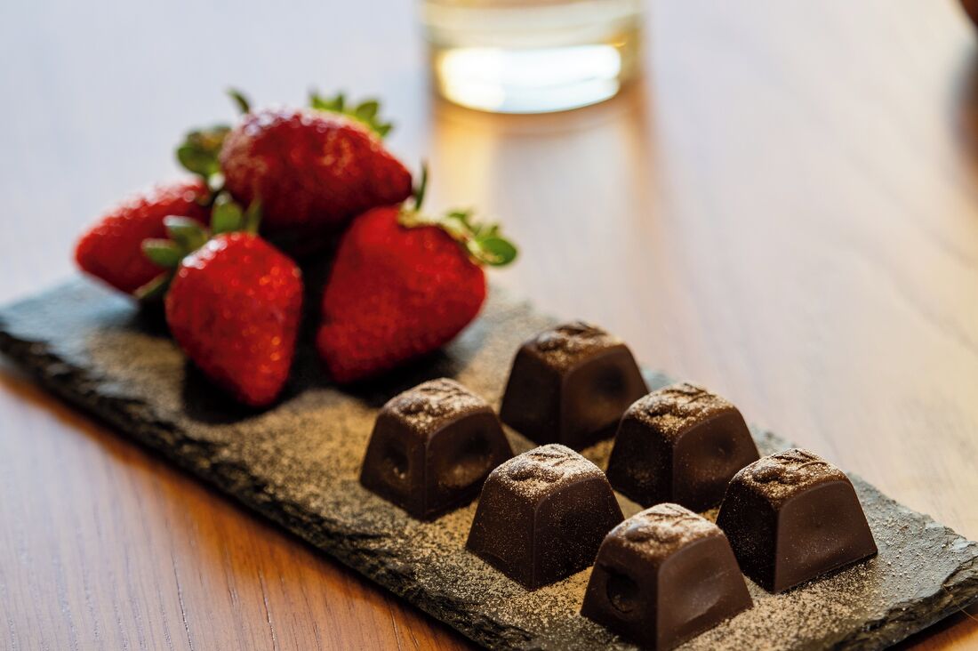 A chocolate dessert on a slate board with strawberries in the background.