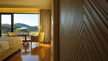 A hotel room with a bed, a table, a chair, and a view of the outdoors.