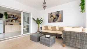 A living room with a sofa, two side tables, and a painting on the wall. - Casa Jerez 14 en Nerja  by Ruralidays (Málaga)