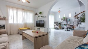 A spacious living room with a wooden coffee table, a sofa, a TV, and a bookshelf. - Casa Jerez 14 en Nerja  by Ruralidays (Málaga)