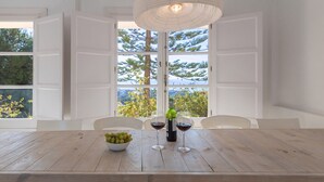 A dining table with a bowl of green grapes and two wine glasses, a bottle of wine, and a pendant light. - Finca Kriek Rincón de la Victoria by Ruralidays (Málaga)