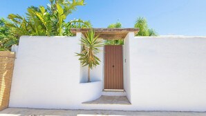 A white-walled building with a wooden door and a small palm tree in front. - Turqueta Chiclana de la Frontera by Ruralidays (Cádiz)
