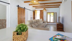 A spacious living room with a large sofa, a wooden ceiling, and a woven basket with greenery. - Turqueta Chiclana de la Frontera by Ruralidays (Cádiz)