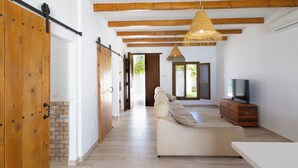 A spacious living area with a sofa, a TV, and a wooden cabinet. - Turqueta Chiclana de la Frontera by Ruralidays (Cádiz)