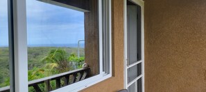 Uma varanda com vista para uma paisagem exuberante e o oceano.