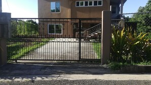Una casa de dos pisos con techo rojo, entrada protegida por una reja y una escalera que lleva al nivel superior.