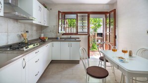 Une cuisine avec des meubles blancs, une cuisinière à gaz et un coin repas comprenant une table et des chaises.