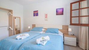 Une chambre d’hôtel avec un lit double, deux tables de chevet avec des lampes, une tête de lit en bois et deux tableaux accrochés au mur.