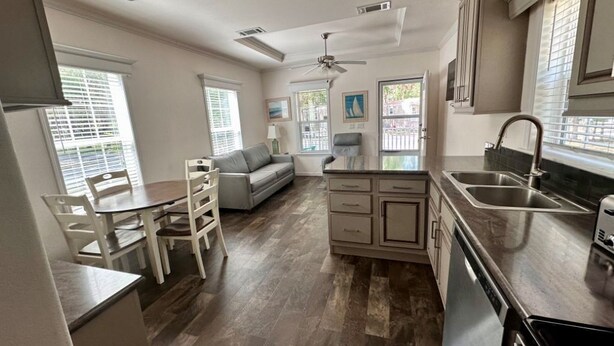 A modern kitchen with a dining area, wooden flooring, and a ceiling fan.