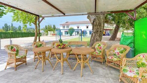 Un patio al aire libre con mobiliario de mimbre y una zona cubierta.