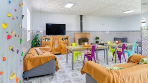 Una sala de estar acogedora con paredes decoradas, una chimenea y un comedor con sillas coloridas.