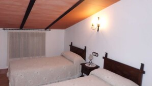 Una camera con due letti, testiere in legno, un comodino con una lampada e una finestra con tenda.