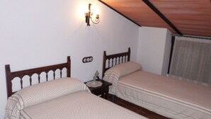 Una camera accogliente e piccola con due letti singoli, un comodino, una sveglia a muro e un lampadario.