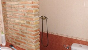 Un bagno con parete in mattoni, una doccia e un water.