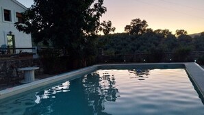 Une piscine rectangulaire avec un mur en pierre et une petite table sur l’un des côtés.
