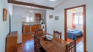 A compact kitchen with a dining area, a washing machine, and a small bedroom with a bed and window. - Zona tranquila cerca de playa Conil de la Frontera by Ruralidays (Cádiz)