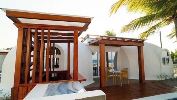 Una estructura de pérgola de madera con piscina y zona de estar al aire libre.