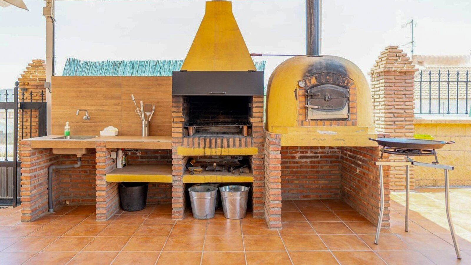 A brick-built outdoor kitchen with a chimney, a sink, and a grill.