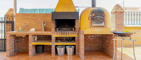 A brick-built outdoor kitchen with a chimney, a sink, and a grill.