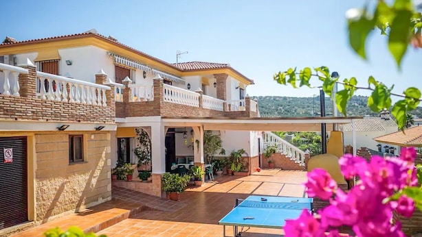 A two-story house with a covered patio area, a balcony, and a view of the surrounding landscape.