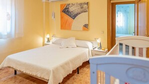 A bedroom with a bed, two bedside tables with lamps, a painting on the wall, and a wooden chair.