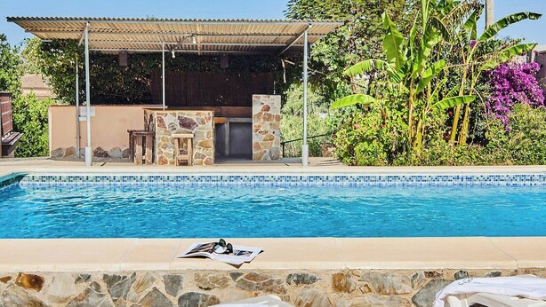 A swimming pool with a stone border, a covered seating area, and lush greenery. - El Mirador Jerez de la Frontera by Ruralidays (Cádiz)