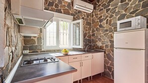 A kitchen with a stone wall, a gas stove, a microwave, and a refrigerator. - El Mirador Jerez de la Frontera by Ruralidays (Cádiz)