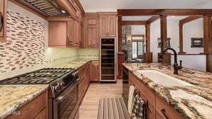 A spacious kitchen with wooden cabinets, a built-in oven, a granite countertop, and a large island with a sink. - Beautiful 4-bedroom house on 8 acres near Fraser - privacy and amazing views!
 (Fraser)