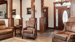 A spacious living room with leather sofas, wooden columns, and a chandelier. - Beautiful 4-bedroom house on 8 acres near Fraser - privacy and amazing views!
 (Fraser)