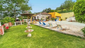 Un jardin bien entretenu, agrémenté d’une fontaine en pierre, d’un espace salon extérieur et d’un coin barbecue.