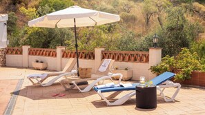 An outdoor seating area with lounge chairs, a table, and a trash bin. - Casa El Limonero Cómpeta by Ruralidays (Málaga)
