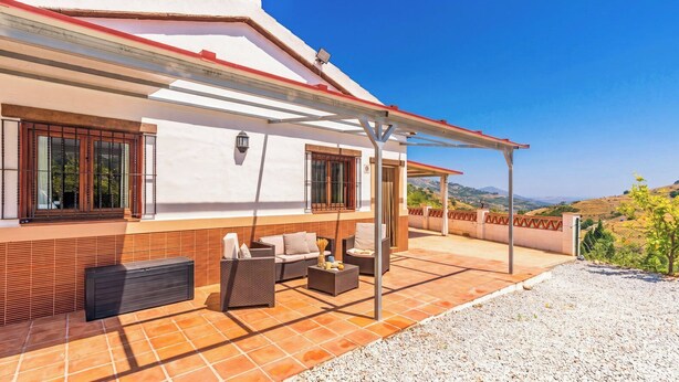 A covered outdoor seating area with a sofa, armchairs, and a coffee table. - Casa El Limonero Cómpeta by Ruralidays (Málaga)