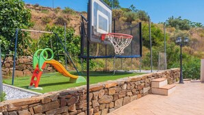 A basketball court with a hoop, a slide, and a swing set. - Casa El Limonero Cómpeta by Ruralidays (Málaga)