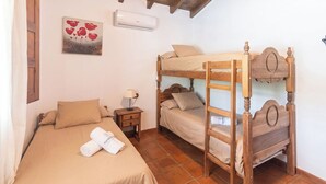 A room with a bunk bed, a single bed, a nightstand with a lamp, and a painting on the wall. - Casa El Limonero Cómpeta by Ruralidays (Málaga)