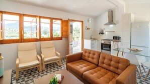 Een moderne keuken met witte kasten, een Bosch koelkast en een eethoek met een glazen tafel.
