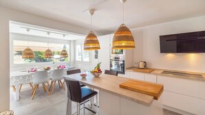 A modern kitchen with a central island, pendant lights, and a view of the outdoors. - Villa Higuera Nerja by Ruralidays (Málaga)