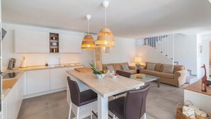 A modern kitchen with white cabinets, a dining table with four chairs, and two hanging wicker pendant lights. - Villa Higuera Nerja by Ruralidays (Málaga)