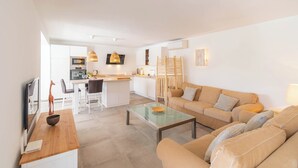 A modern living room with a sofa, coffee table, and a dining area with chairs and a kitchen in the background. - Villa Higuera Nerja by Ruralidays (Málaga)
