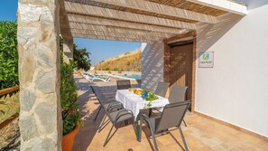 Eine Terrasse mit Tisch für zwei Personen, mit Blick auf einen Pool und eine Berglandschaft.