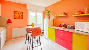 A kitchen with a window, a radiator, a table with chairs, and a microwave on the counter.