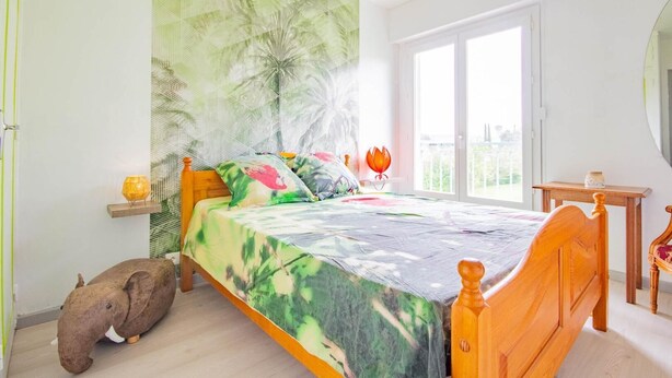 A bedroom with a bed, a wooden headboard, a nightstand, a lamp, and a small elephant figurine.