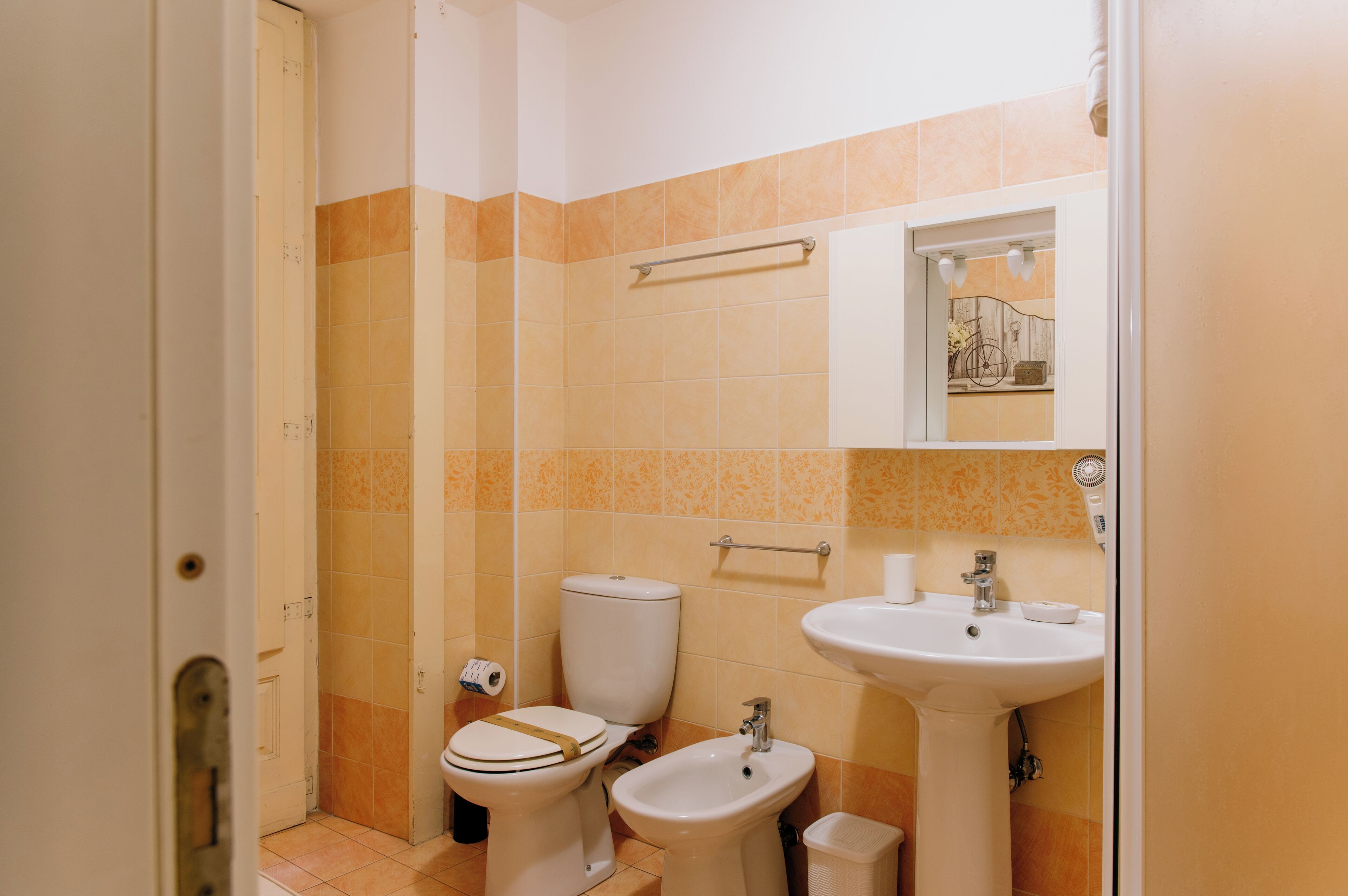 A bathroom with a toilet, bidet, sink, and a towel rack.