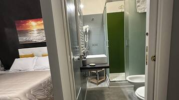 Quarto de hotel com cama, banheiro com chuveiro e vaso sanitário.