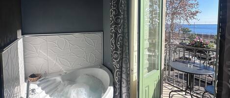 A bathroom with a large bathtub, a shower, and a view of the outdoors.