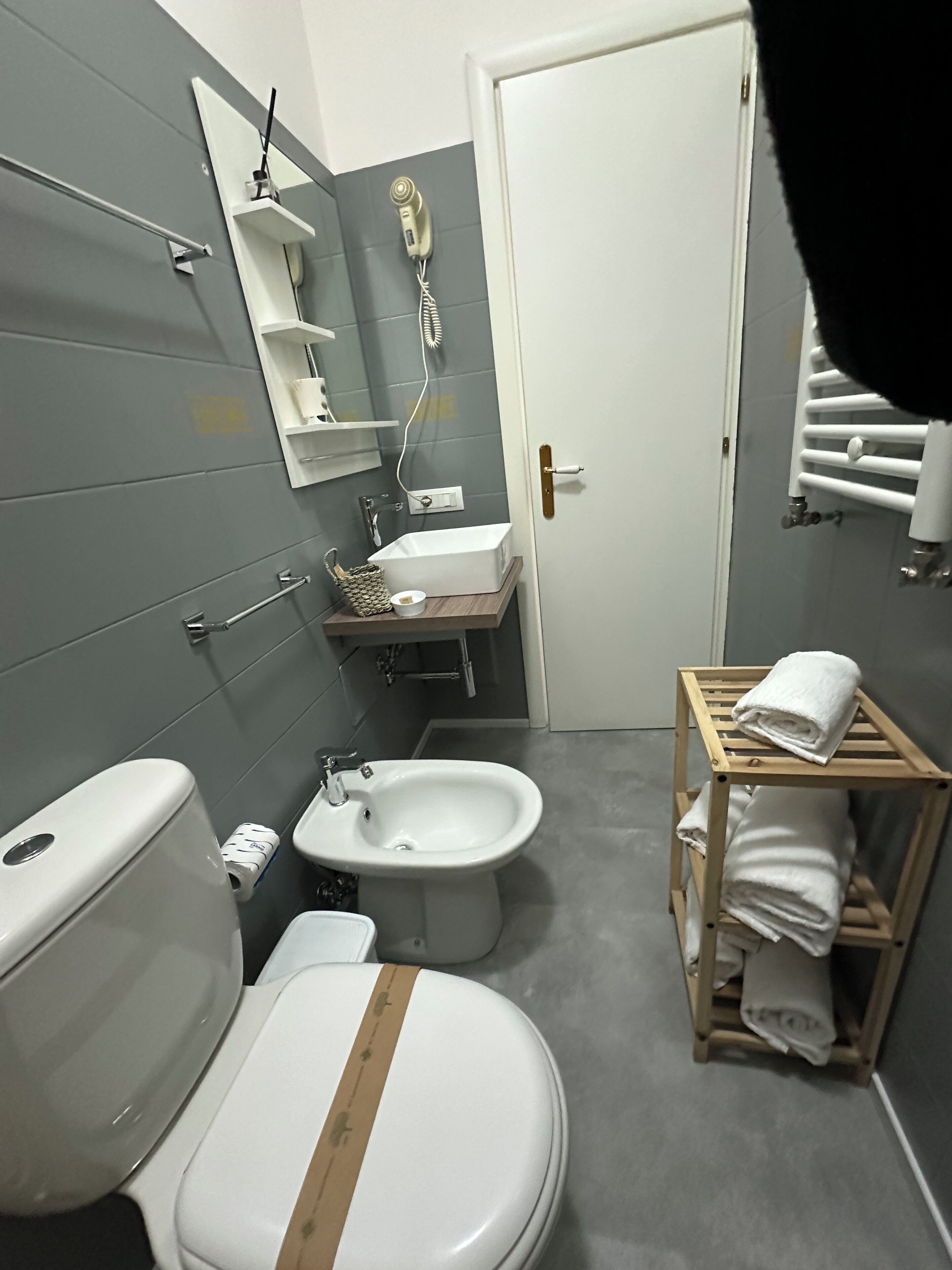 A bathroom with a toilet, bidet, sink, and a towel rack.