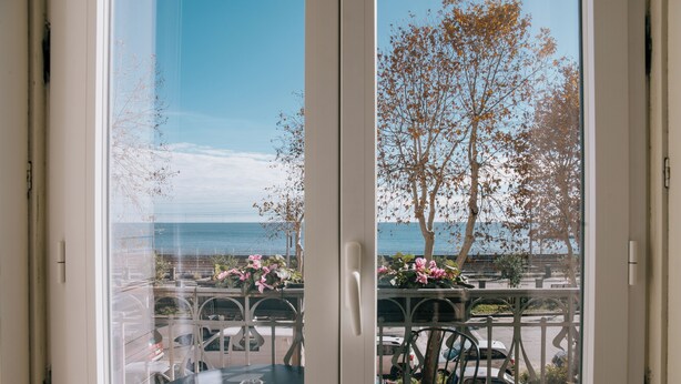 A view from a balcony with a table and chairs, overlooking a parking area and trees. - B&B I Puritani (Catania)