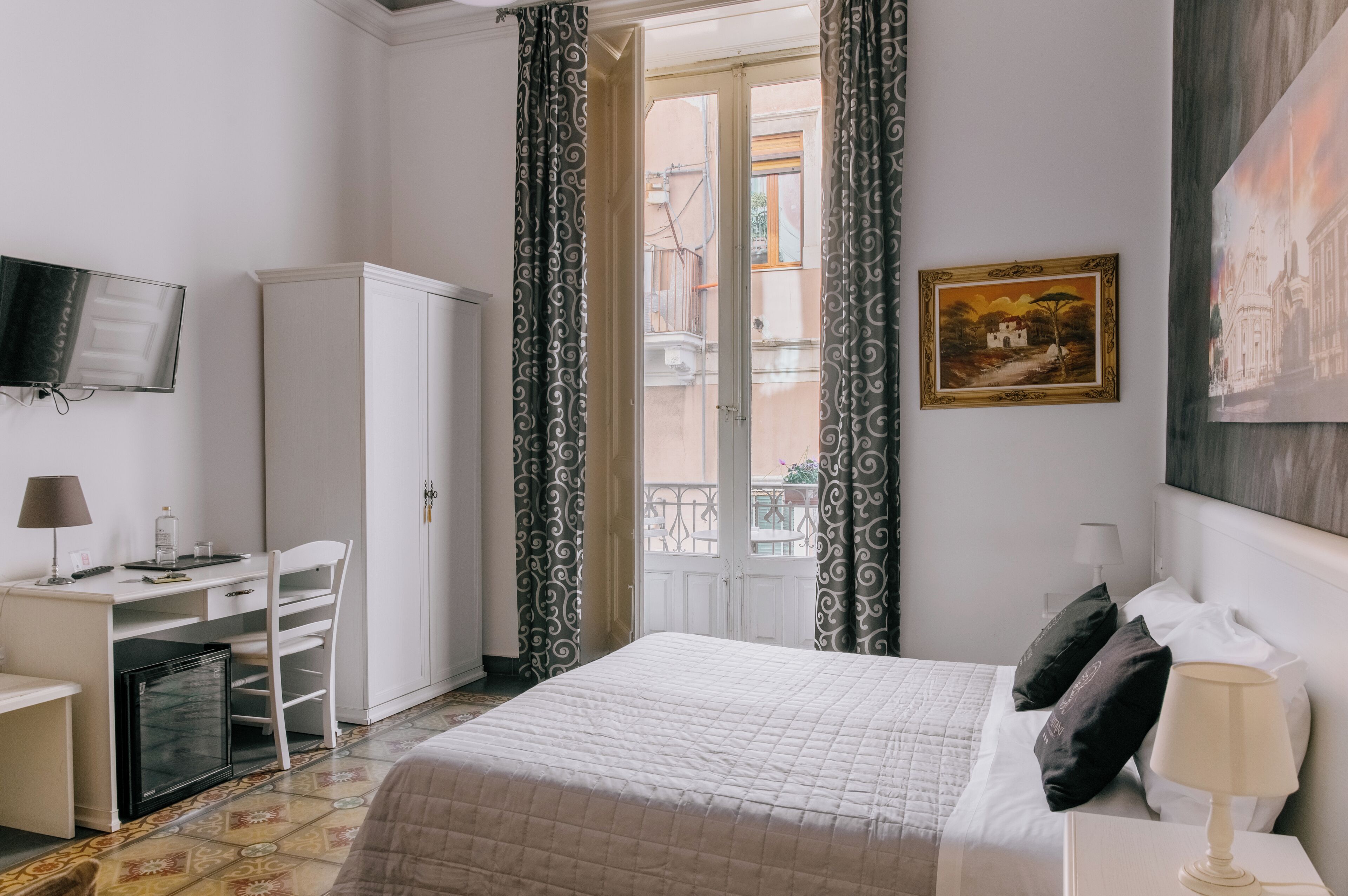 Una habitación de hotel con cama, escritorio, silla y televisión en la pared.