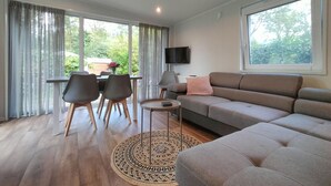A modern living room with a grey sofa, a round coffee table, and a dining area with chairs and a table. - Pet friendly home in Mariënberg (Mariënberg)